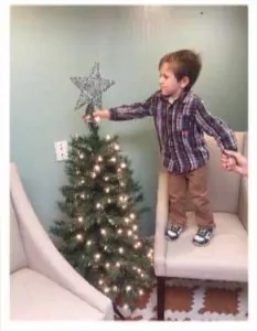 child putting star on a christmas tree