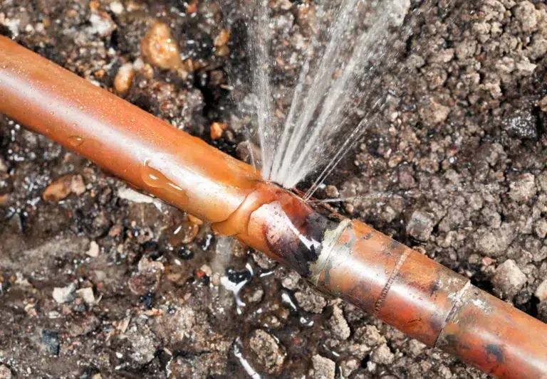 Copper water main pipe underground with a leak