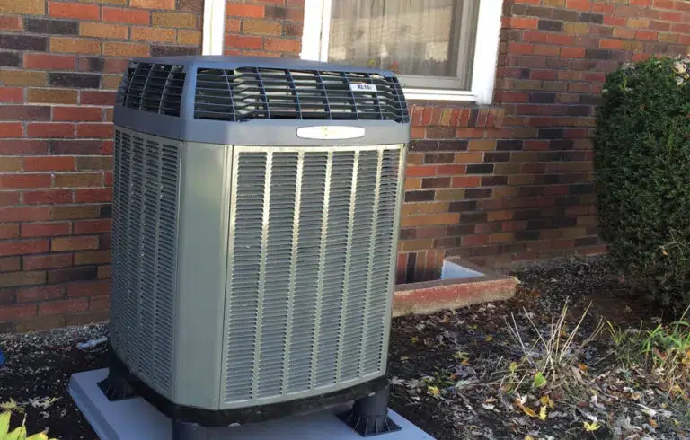 outdoor AC unit installed next to a brick home.
