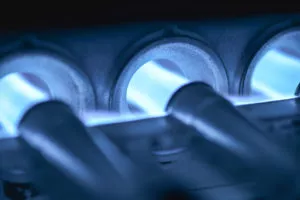 Gas furnace pilot lights ignited, burning blue.