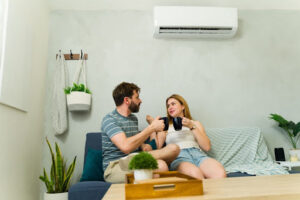 Couple sitting on couch underneath ductless AC unit.